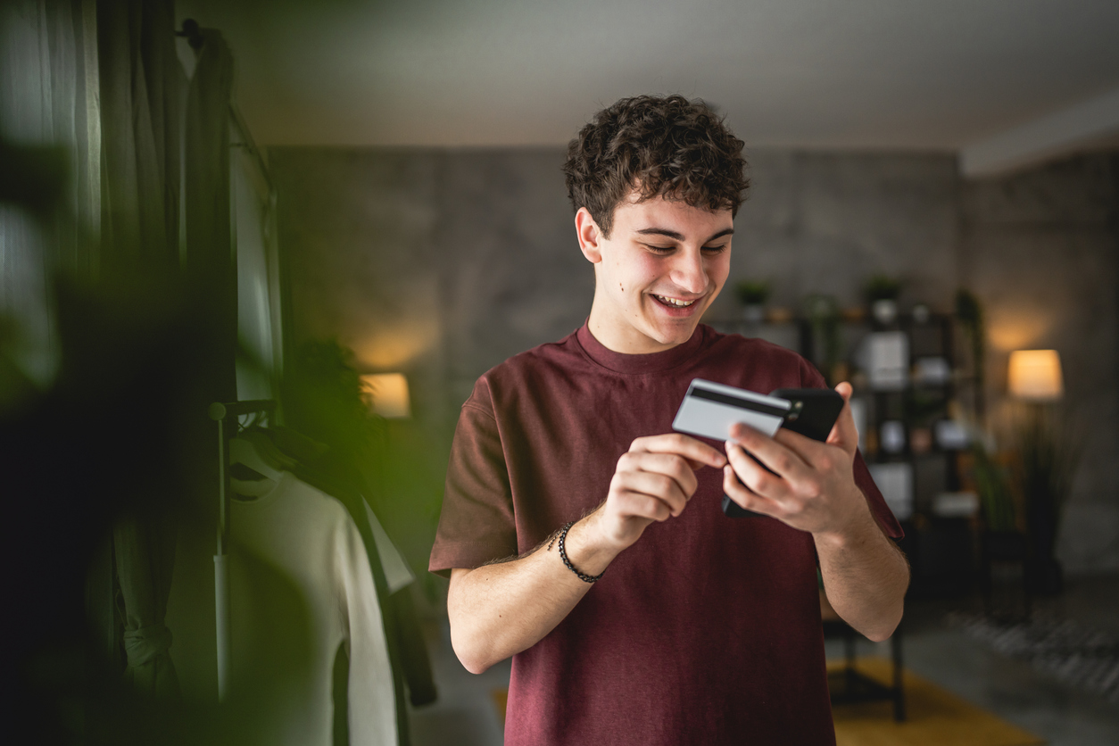 One teenager young man caucasian male sit at home use credit card shopping online use internet for online purchase active modern e-banking
