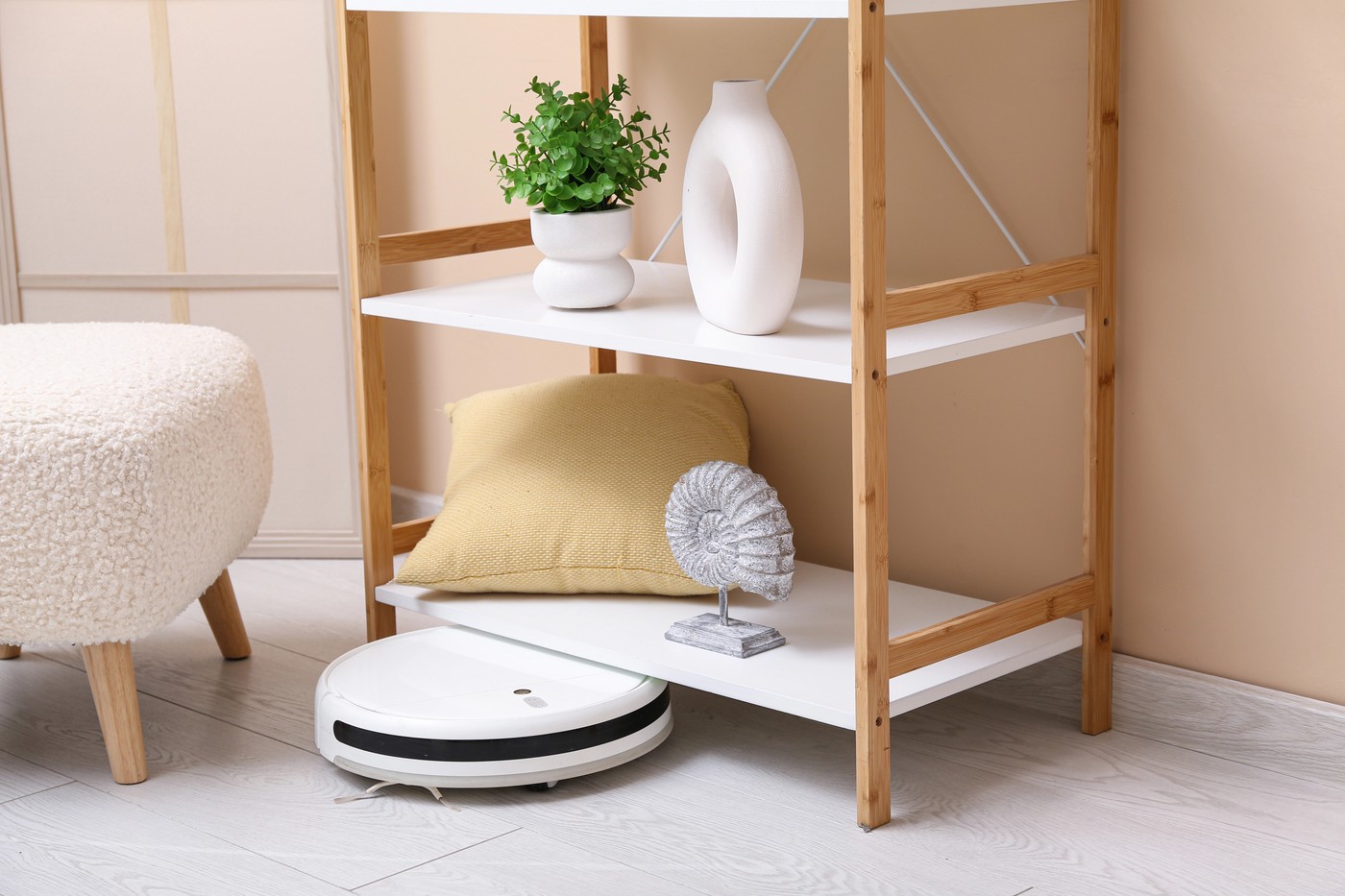 Modern robot vacuum cleaner under shelving unit at home