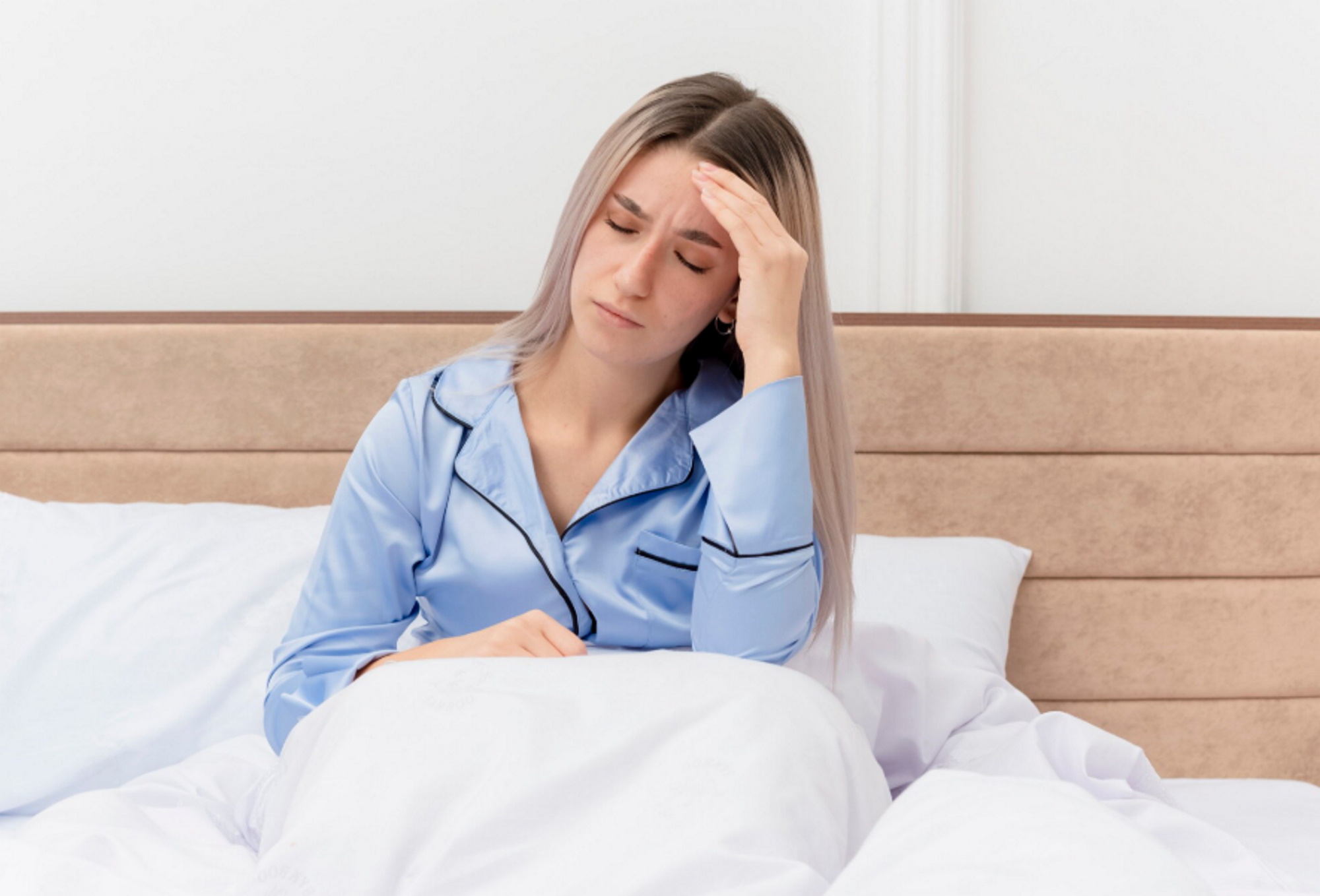 young-beautiful-woman-blue-pajamas-sitting-bed-touching-her-head-having-headache-bedroom-interior-3010