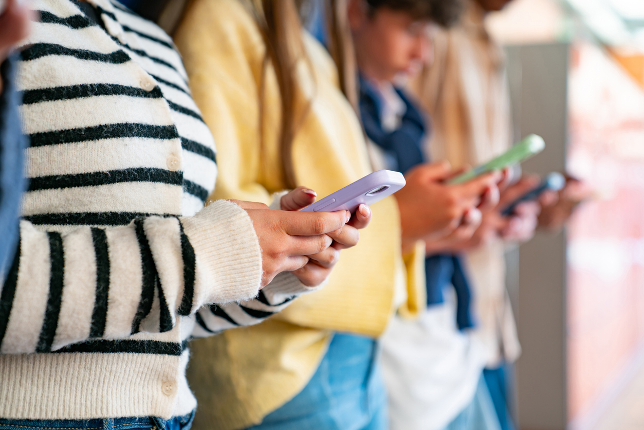 Group of isolated Gen Z teenagers in a row using their phones - digital native concepts